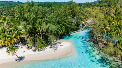 Lush palms sway gently by the picturesque shore of Koh Kood, Thailand. Crystal-clear waters glisten...
