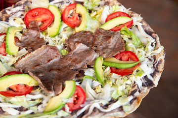 Tlayuda is a thin, crispy tortilla topped with black beans, beef jerky, tomato and avocado. Is a traditional Mexican food from Oaxaca.