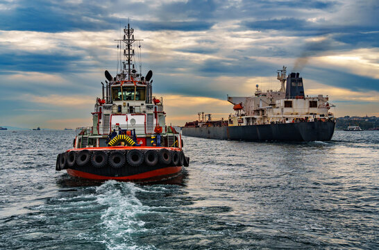 A large tanker ship and tug boat sails along the Bosphorus against the background of Istanbul, Turkey, a view from a pleasure boat