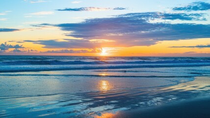 Obraz premium Serene sunset over the ocean, waves gently lapping the shore, reflecting the vibrant sky.