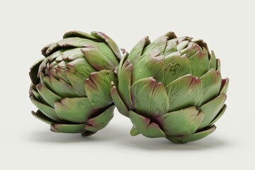 Two fresh artichokes, vibrant green with reddish hues, ready for cooking.