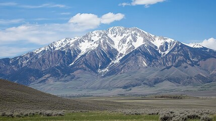 Majestic Mountain Peak: A majestic snow-capped mountain peak rises against a clear blue sky, its rugged slopes reaching for the heavens.