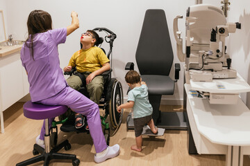 Naklejka premium Optometrist examining patient with cerebral palsy as brother watches on