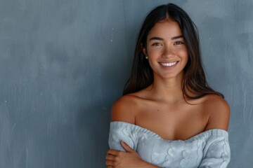 Fototapeta premium Latin woman with crossed arms smiling against grey wall.