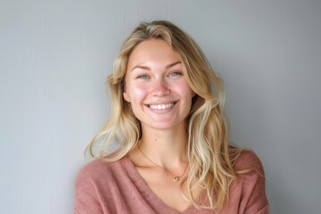 Fototapeta premium Happy woman with fair hair smiling at camera in studio.