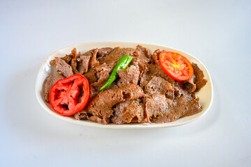 Turkish  Traditional Ramadan doner kebab with tasty tomato sauce and rice or turkish pilav in white plate on table background. Lavash doner kebab ( doner zurna durum )  Pilavustu Doner Iskender kebap