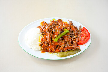 Turkish  Traditional Ramadan doner kebab with tasty tomato sauce and rice or turkish pilav in white plate on table background. Lavash doner kebab ( doner zurna durum )  Pilavustu Doner Iskender kebap