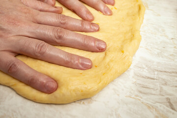 Woman hands fingers pressing on yellow raw dough, focaccia making process, close up texture