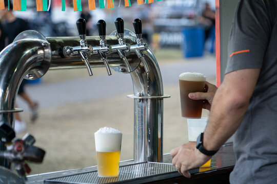 Bar tender sirviendo deliciosa cerveza roja tirada en feria al aire libre