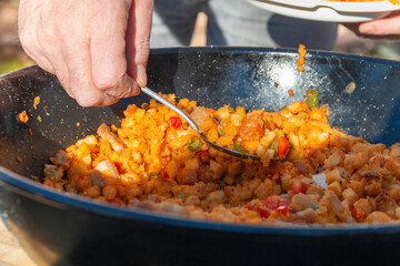 Preparing La Mancha or Castilian migas as a family where everyone eats with a spoon from the same pot. we can appreciate all its ingredients, chistorra, bacon, bread, pepper...