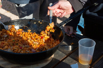 Preparing La Mancha or Castilian migas as a family where everyone eats with a spoon from the same pot. we can appreciate all its ingredients, chistorra, bacon, bread, pepper...
