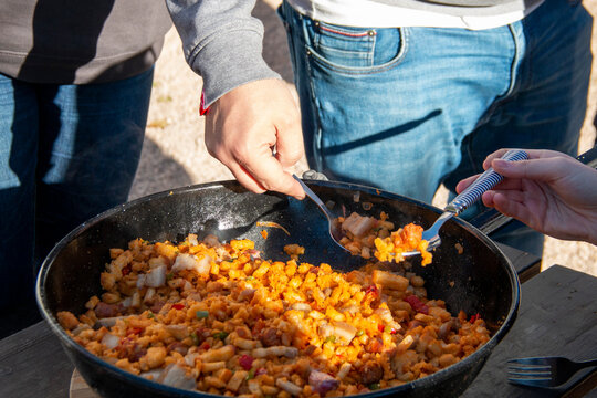Preparing La Mancha or Castilian migas as a family where everyone eats with a spoon from the same pot. we can appreciate all its ingredients, chistorra, bacon, bread, pepper...