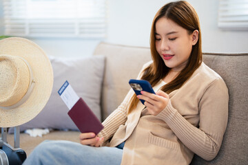 Woman packs travel bag and booking hotel online using her smart phone.Woman buying flight tickets and booking hotel using her mobile phone at home and packing travel bag for vacation.