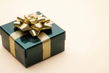 Obraz premium Elegant Green Gift Box with Golden Bow on Cream Background Perfect for Celebrations, Birthdays, or Holidays, Captured in Soft Lighting and Raw Style for High Resolution Use