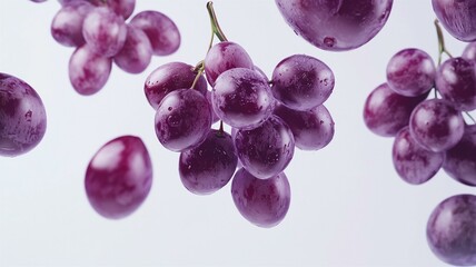 High-quality view of vibrant purple grapes in mid-air with stems and shiny texture on white background
