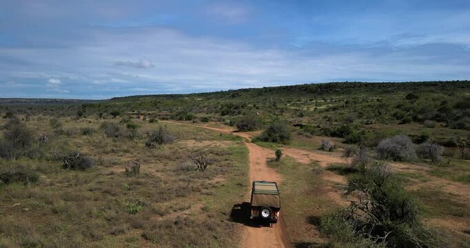 A 4x4 or safari car drives through the savannah