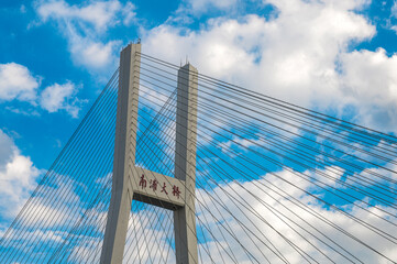 A close-up of the Nanpu Bridge in Shanghai, China, in a blue sky and white clouds