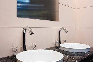 Two sinks with a mirror above them in the bathroom interior. One sink has a glass cup on it