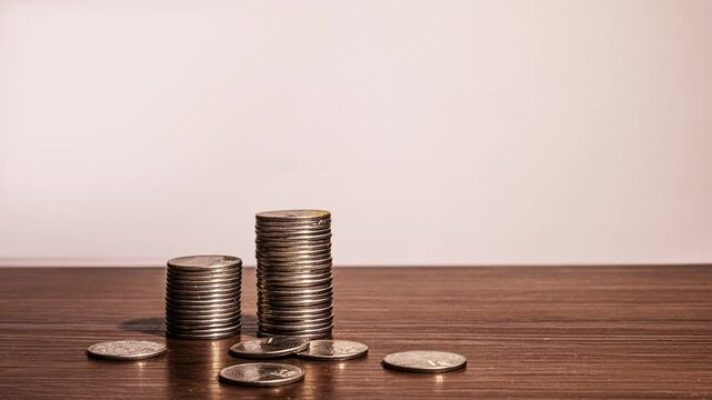 stopmotion animation of pile Stacks of Ghanaian cedi and pesewas coins rising piling up on brown wooden desk