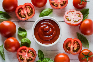 Fototapeta premium White wooden surface holds a bowl of red ketchup surrounded by fresh tomatoes