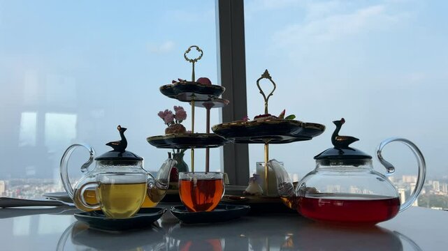 Luxury lifestyle. Elegant young lady in white dress and straw hat pouring hot tea and enjoy sweet food in cafe with sea view. Romantic afternoon tea in restaurant