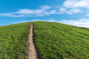 Path on a green hill leading up against a blue sky. Beautiful landscape.