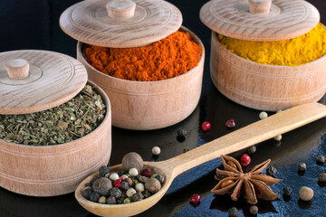 aromatic spices. wooden dishes with spices. black red and allspice, turmeric ginger basil and other spices in the kitchen. natural ingredients. colorful, multi-colored condiments. cooking, still life