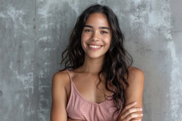 Fototapeta premium Portrait of smiling Latin woman with crossed arms on grey wall.