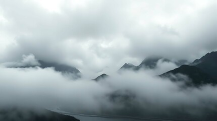 Obraz premium A serene vista of mountains enveloped in a thick layer of fog or clouds