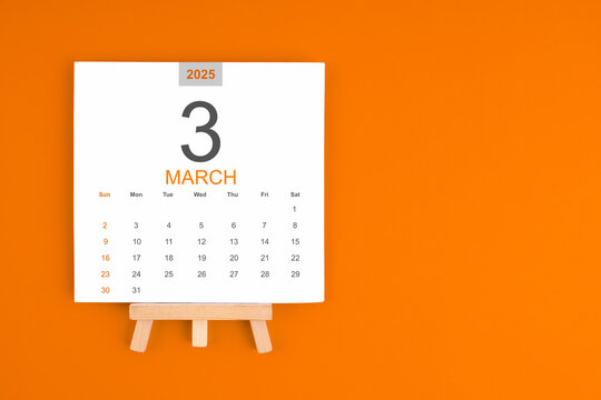 Calendar page for March 2025 with wood easel on orange background.