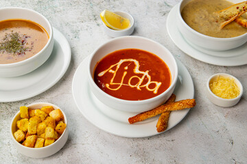 Savory soups with bread sticks and croutons served on white plates