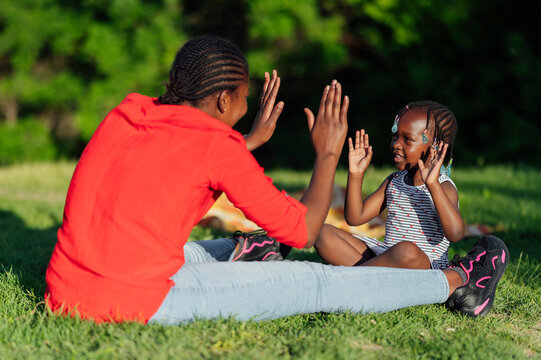 Mother and daughter playing clapping in a park