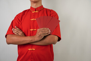 Smiling young asian man wearing red traditional chinese clothing is holding many red envelopes,...
