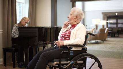An elderly woman enjoys piano music played by a family member in a care home. The warm atmosphere fosters togetherness during a family visit.