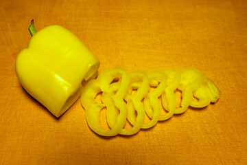 Yellow bell pepper sliced into spiral shapes on wooden surface