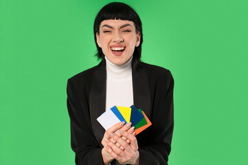 Young woman smiles broadly while holding colorful cards against a bright green background