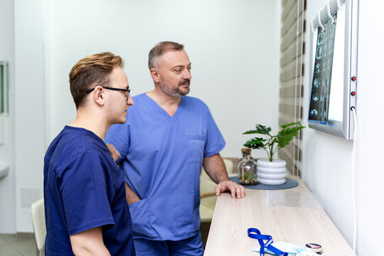 Doctors review patient scans. Two healthcare workers study patient scans on a display in a modern medical facility, discussing findings carefully.