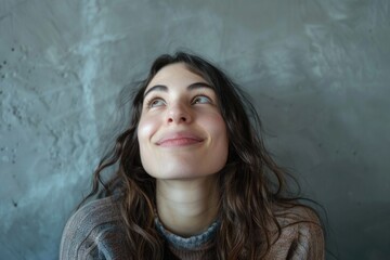 Thoughtful expression, hand on chin, against gray wall background