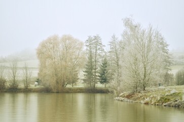 Winter landscape with a frozen lake and snow-covered trees. frost on the trees. Winter foggy landscape