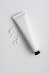 White cosmetic tube with cream smear