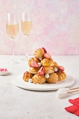 A mound of choux pastry pastries with vanilla custard cream, decorated with caramel and freeze-dried strawberries