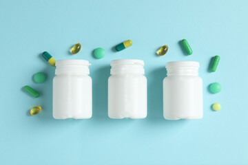 White bottles with pills on a color background