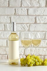 Bottle of white wine with grapes and glasses on table