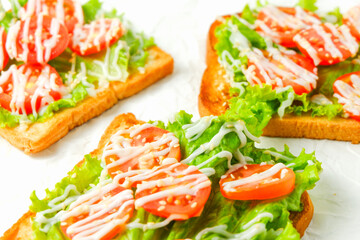 Colorful toast healthy sandwich with green lettuce and red tomato isolated on white parchment paper