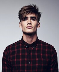 Obraz premium Stylish male model posing in plaid shirt, highlighting contemporary haircut with confident demeanor during professional photoshoot