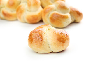 Yeast bread bun with defocused pile of buns. Golden baked yeast bread knots. Braided knot roll with...