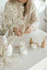 Vertical frame of an influencer blogger arranging neutral-toned props on a smooth marble counter for content creation
