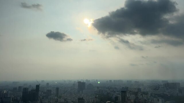 gray sky over ho chi minh city sun comes out skyscrapers in fog Dramatic cloud moving with beautiful twilight dusk scene of hazy city. Sunset time lapse scenery.