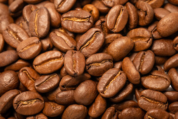 Fragrant roasted Arabica coffee beans in close-up. The background is dark brown from coffee beans