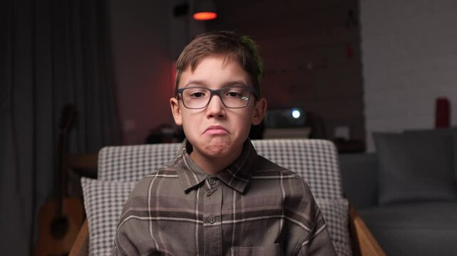 Sad child wearing glasses making a frustrated face. Young gamer playing videogames